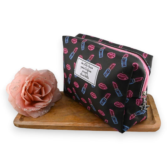 Schwarze Kosmetiktasche mit Lippen- und Lippenstiftmuster, rosa Rose und Holzbrett. Französischer Spruch auf Etikett.