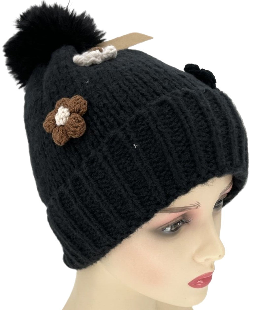 Schwarze Strickmütze mit Bommel, gestrickter Blume und weißer Schleife, auf Schaufensterpuppe präsentiert