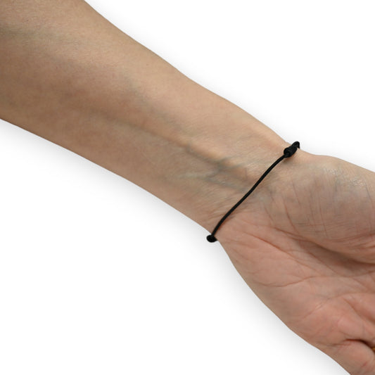 Feines schwarzes elastisches Armband mit minimalistischem Design am Handgelenk einer Person auf weißem Hintergrund