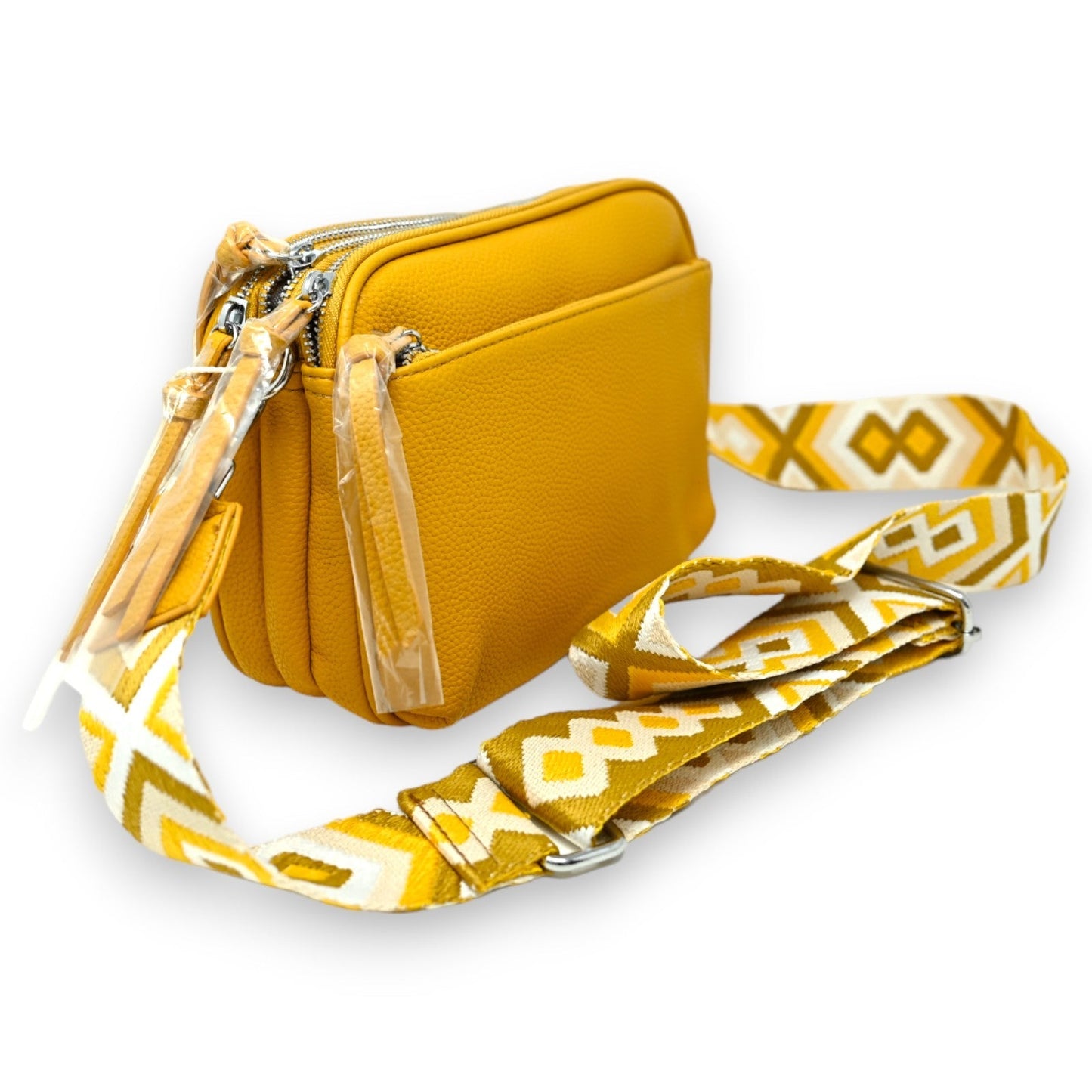 Senfgelbe quadratische Umhängetasche mit Reißverschluss und geometrisch gemustertem Schulterriemen auf weißem Hintergrund