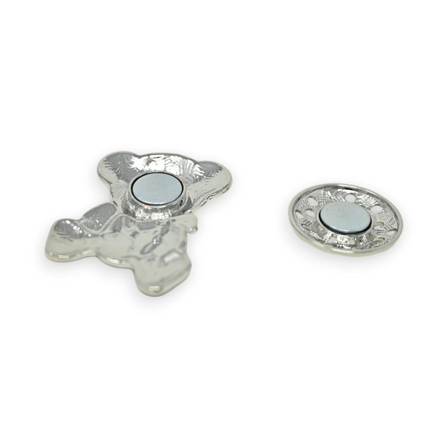Silberne magnetische Bärenbrosche und runde Magnetscheibe mit dekorativen Mustern, auf weißem Hintergrund