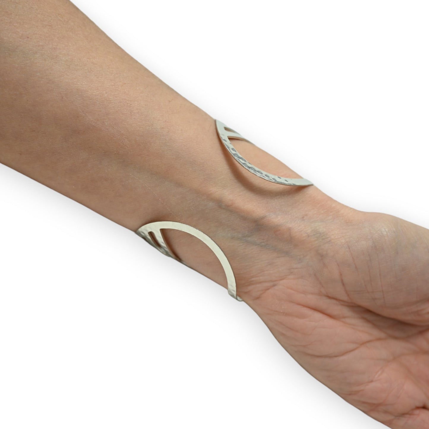 Eleganter silberner Armreif mit geschwungenem Design auf Handgelenk, minimalistischer Schmuck mit offenem Muster