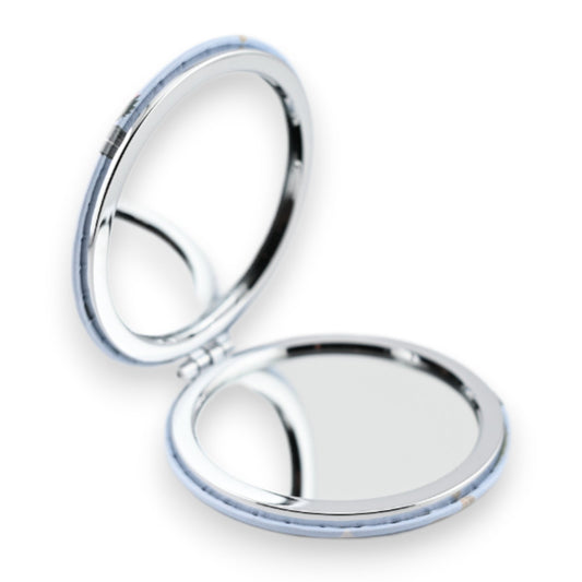 Runder Taschenspiegel mit silbernem Rahmen, halb geöffnet, auf weißem Hintergrund. Kompakter Klappspiegel für unterwegs.