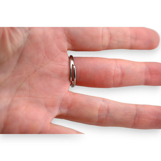 Silberner ovaler Stahlring an einem Finger, zeigt die Passform und das minimalistische Design des Schmuckstücks
