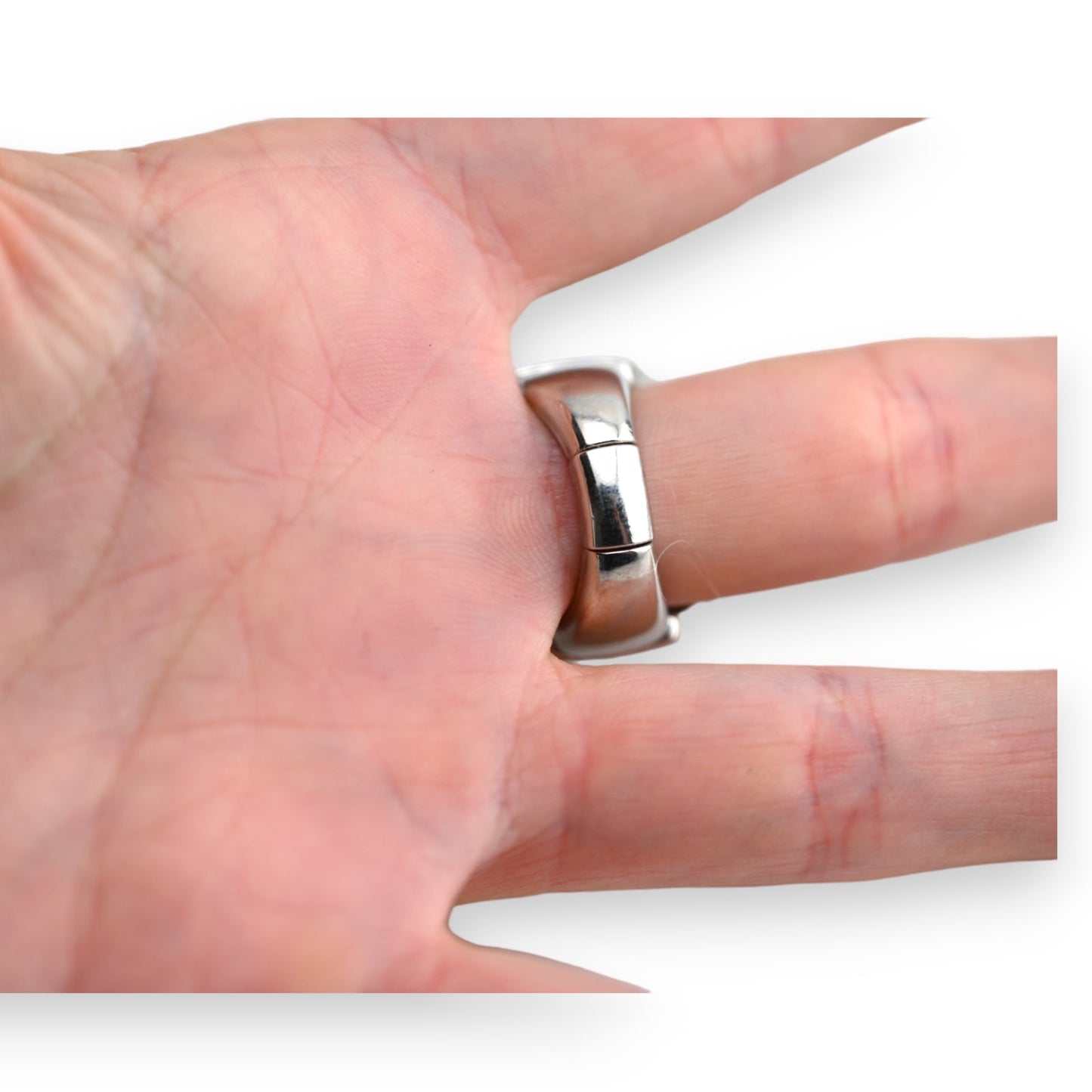 Nahaufnahme einer Hand mit einem silbernen Ring am Finger, der Segmente oder Linien auf der Oberfläche zeigt