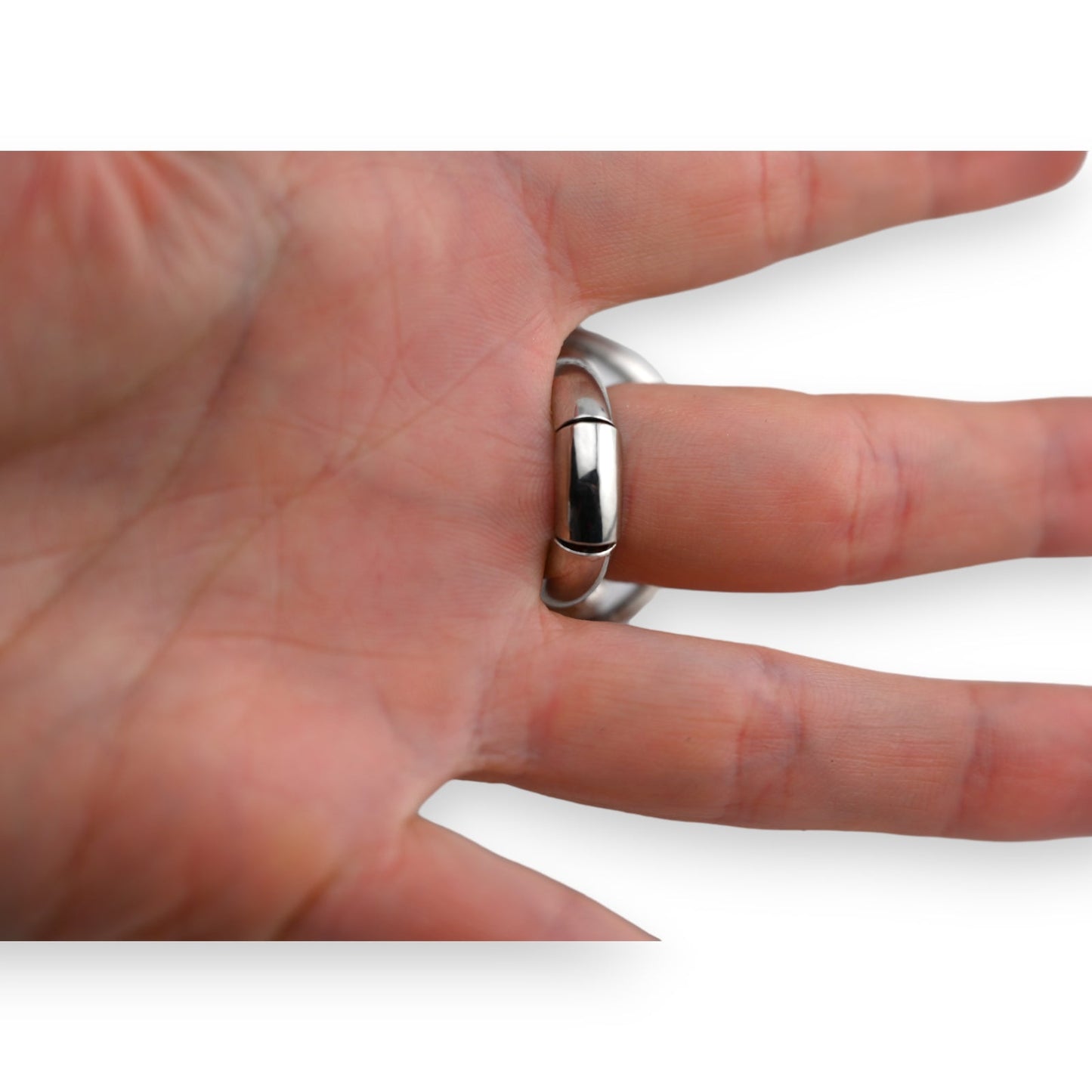 Nahaufnahme eines glänzenden Silberrings am Ringfinger einer Hand, glatter Ehering auf Hautoberfläche