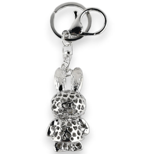 Silberner Schlüsselanhänger mit Hasenfigur, texturierter Oberfläche und grauem Rock. Dekoratives Accessoire mit Herzmuster.
