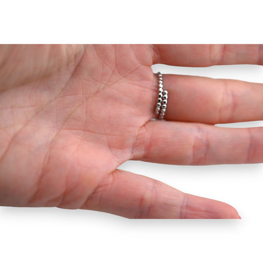 Silberner Stahlring mit ovalen und runden Strasssteinen auf einer geöffneten Handfläche, Nahaufnahme