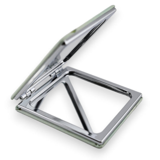 Aufgeklappter silberner Taschenspiegel mit quadratischem Spiegel und Scharnieren, auf weißem Hintergrund