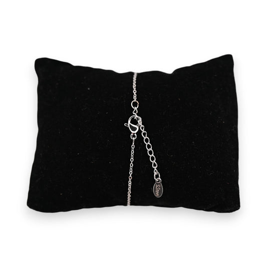 Silbernes Stahlarmband mit Engelanhänger auf schwarzem Samtkissen, filigrane Kette mit Verschluss und Markenplakette