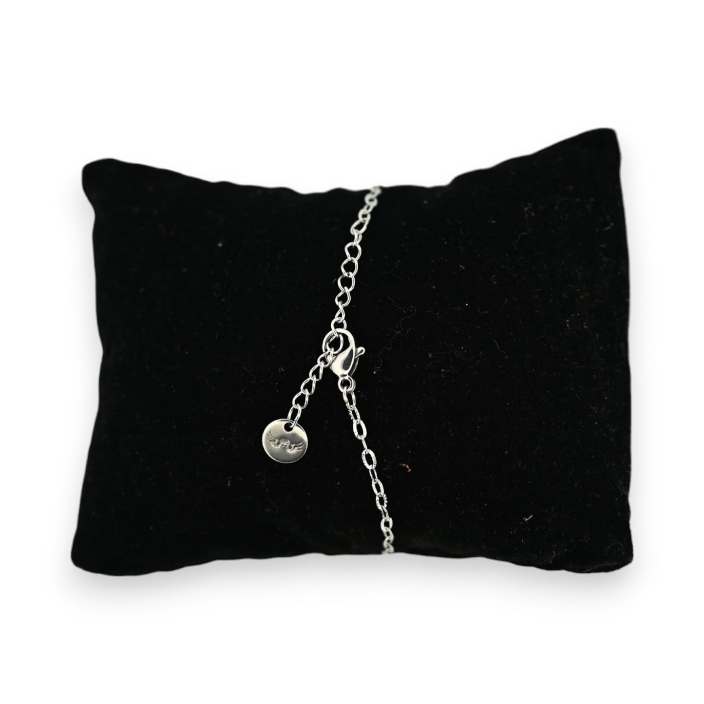 Silbernes Stahlarmband auf schwarzem Samtkissen, mit feiner Kette und rundem Anhänger, elegantes Schmuckstück