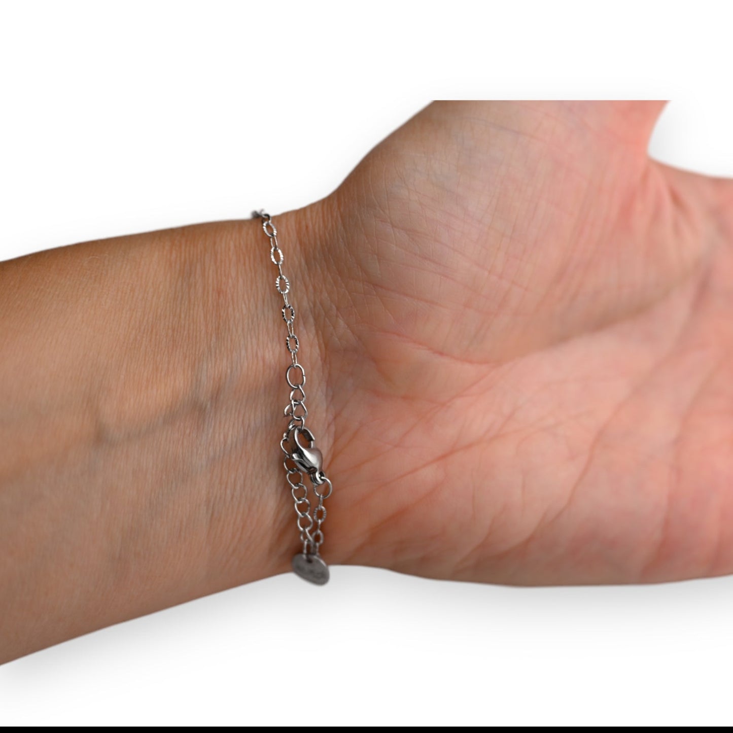 Filigrane Stahlarmkette mit zwei geschmiedeten Ringen als Anhänger, am Handgelenk getragen
