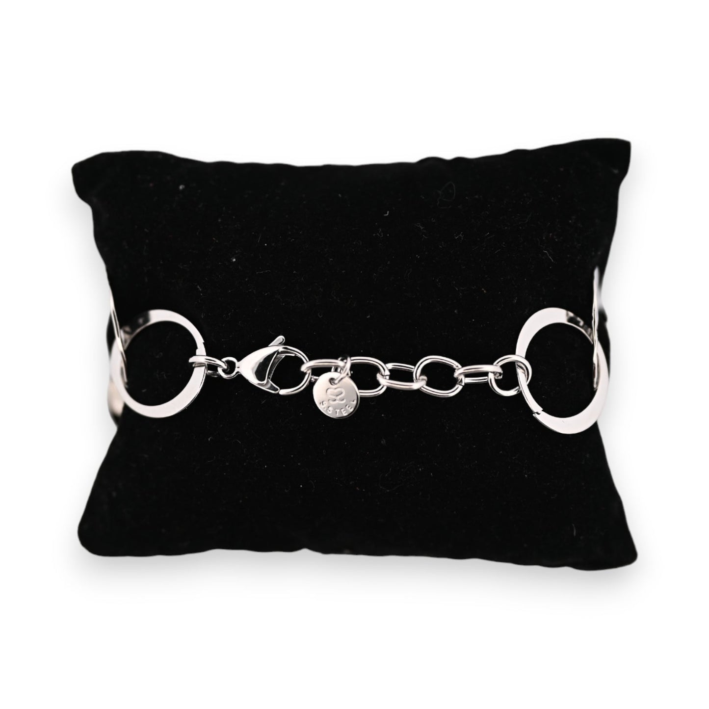 Silbernes Stahlarmband auf schwarzem Kissen, große ringförmige Glieder, Karabinerverschluss und kleiner Markenanhänger