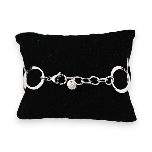 Silbernes Stahlarmband auf schwarzem Kissen, große ringförmige Glieder, Karabinerverschluss und kleiner Markenanhänger