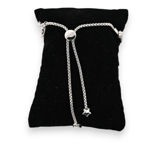 Silbernes Stahlarmband auf schwarzem Samtkissen, verstellbar mit glänzendem Schiebeverschluss und hängenden Sternanhängern