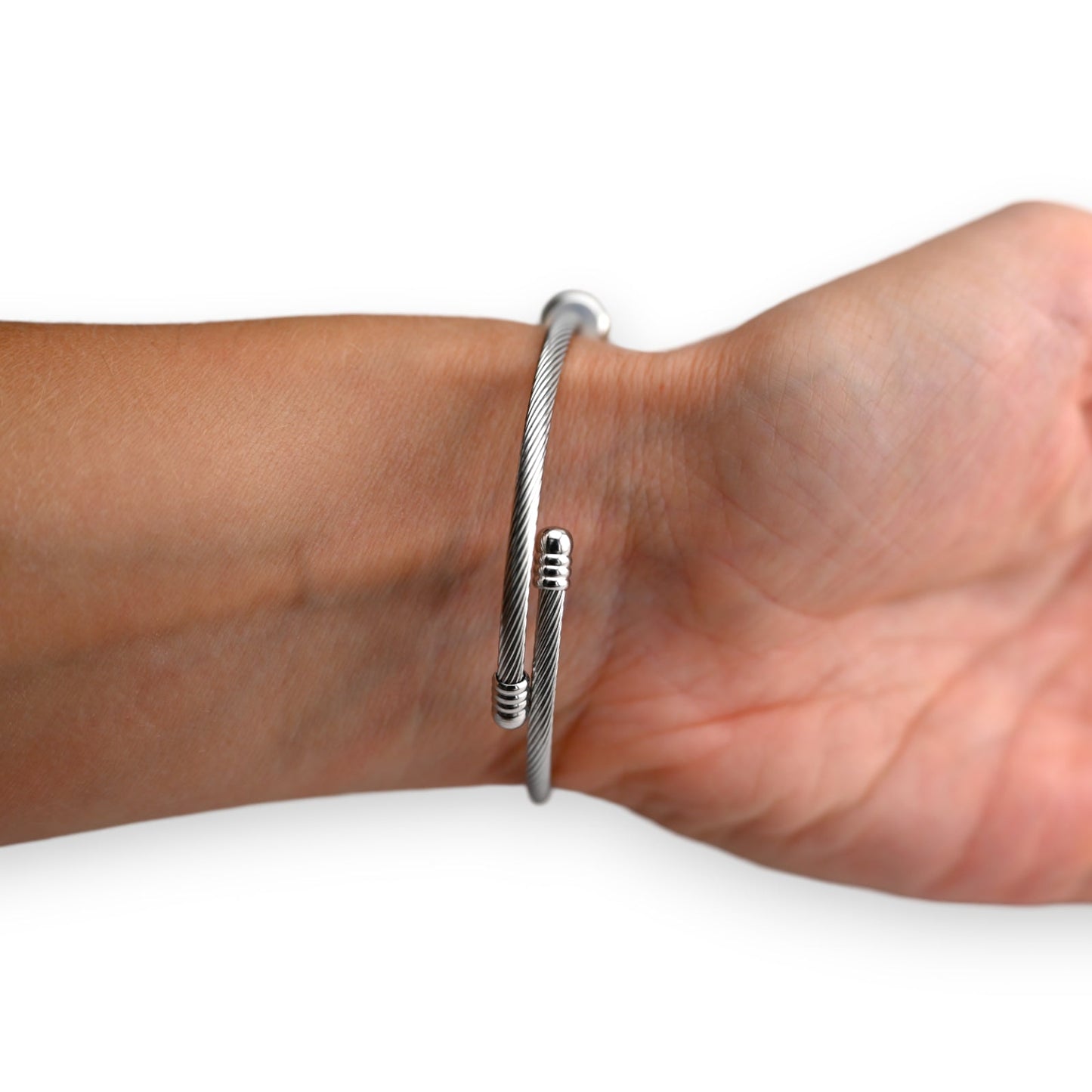 Silbernes Kabelarmband mit spiralförmigen Enden, eng um ein Handgelenk gelegt, auf weißem Hintergrund