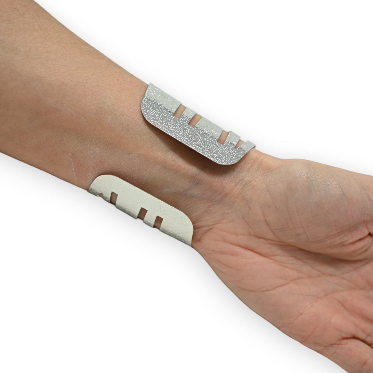 Zwei silberne, strukturierte Manschetten mit Schlitzen auf einem Handgelenk. Minimalistisches ethnisches Schmuckdesign.