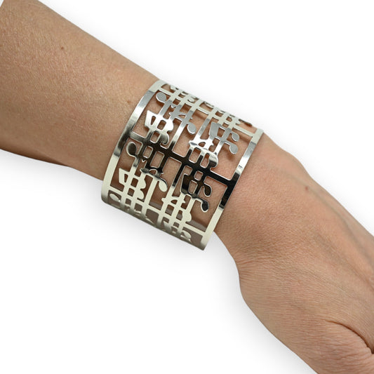 Breites silbernes Armband mit filigranem Musiknoten-Muster auf Handgelenk, moderner Schmuck für Musikliebhaber