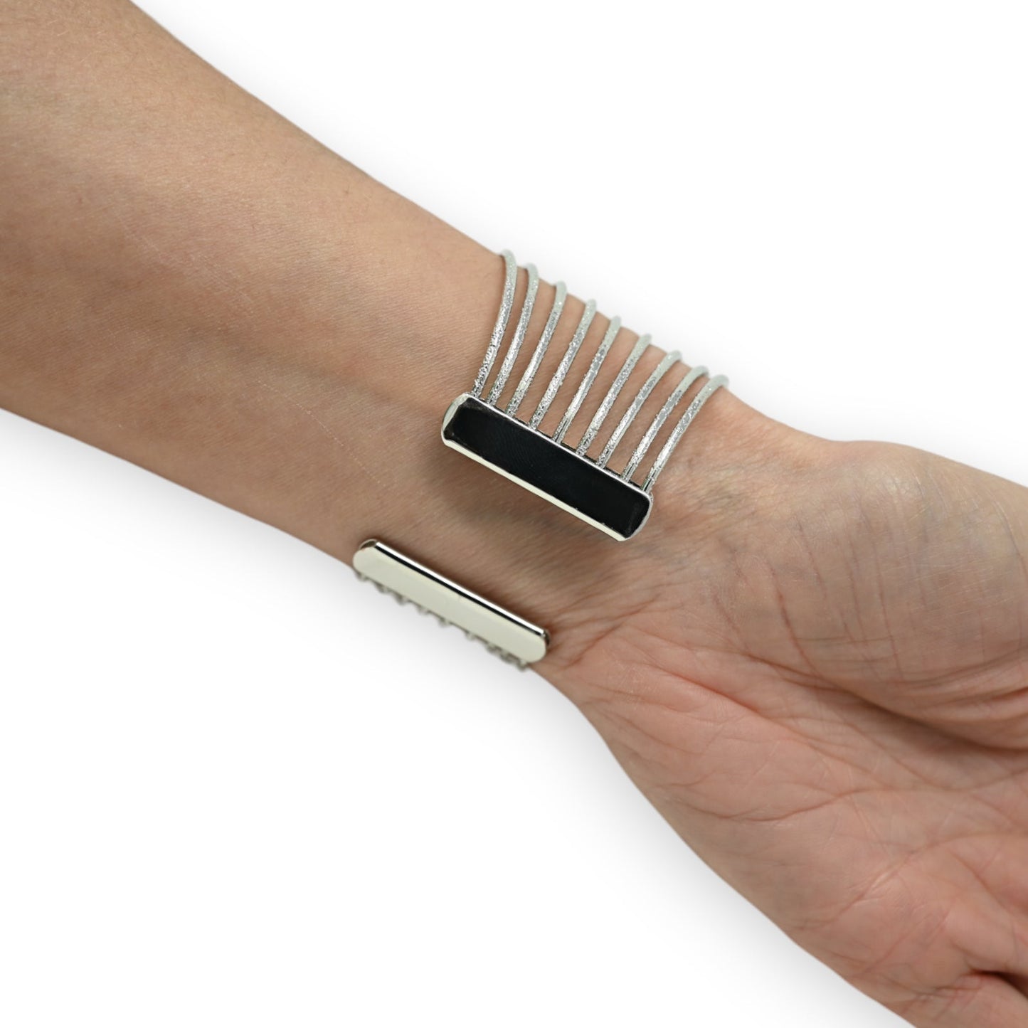 Silbernes Manschettenarmband am Handgelenk, mit schwarzem Rechteck und feinen durchbrochenen Metallstreifen
