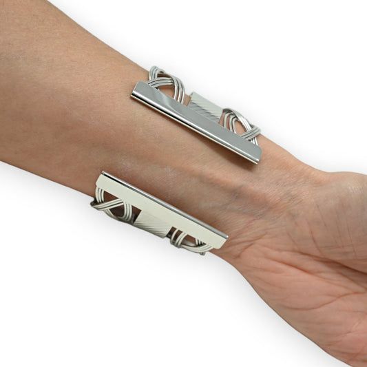 Silberne Manschettenarmbänder mit geometrischem Design auf Handgelenk, moderne Schmuckstücke mit linearen Elementen