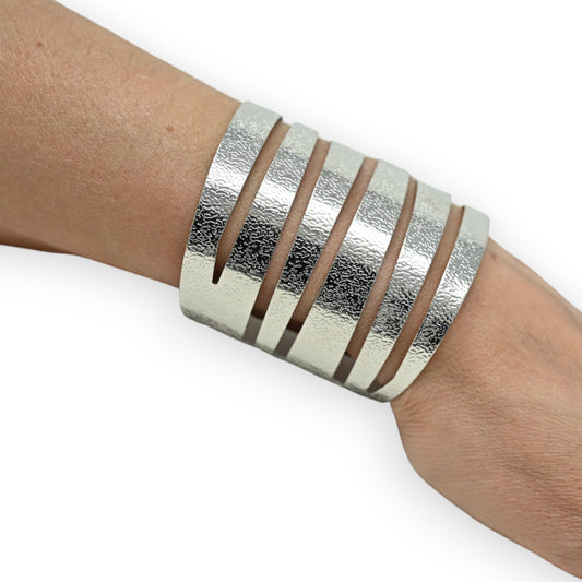 Silbernes Manschettenarmband mit mehreren parallelen Streifen auf einem Handgelenk, modernes ethnisches Design