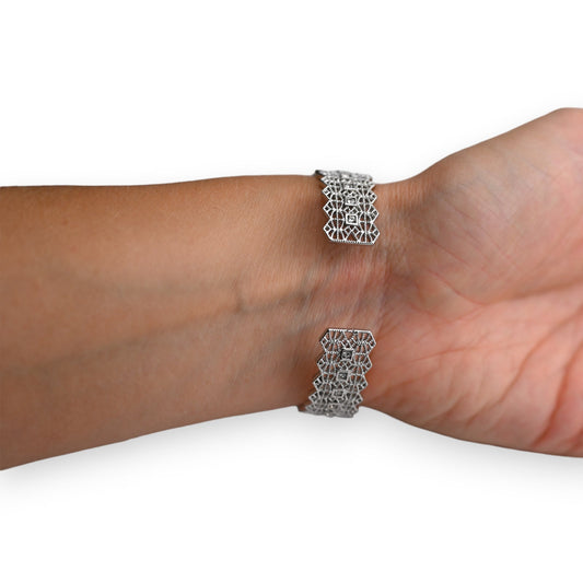 Filigranes Silberarmband mit geometrischem Spitzenmuster am Handgelenk getragen, detaillierte Nahaufnahme