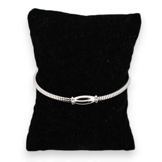 Silberfarbenes Stahlarmband auf schwarzem Samtkissen, mit eleganter länglicher Schließe als zentrales Element