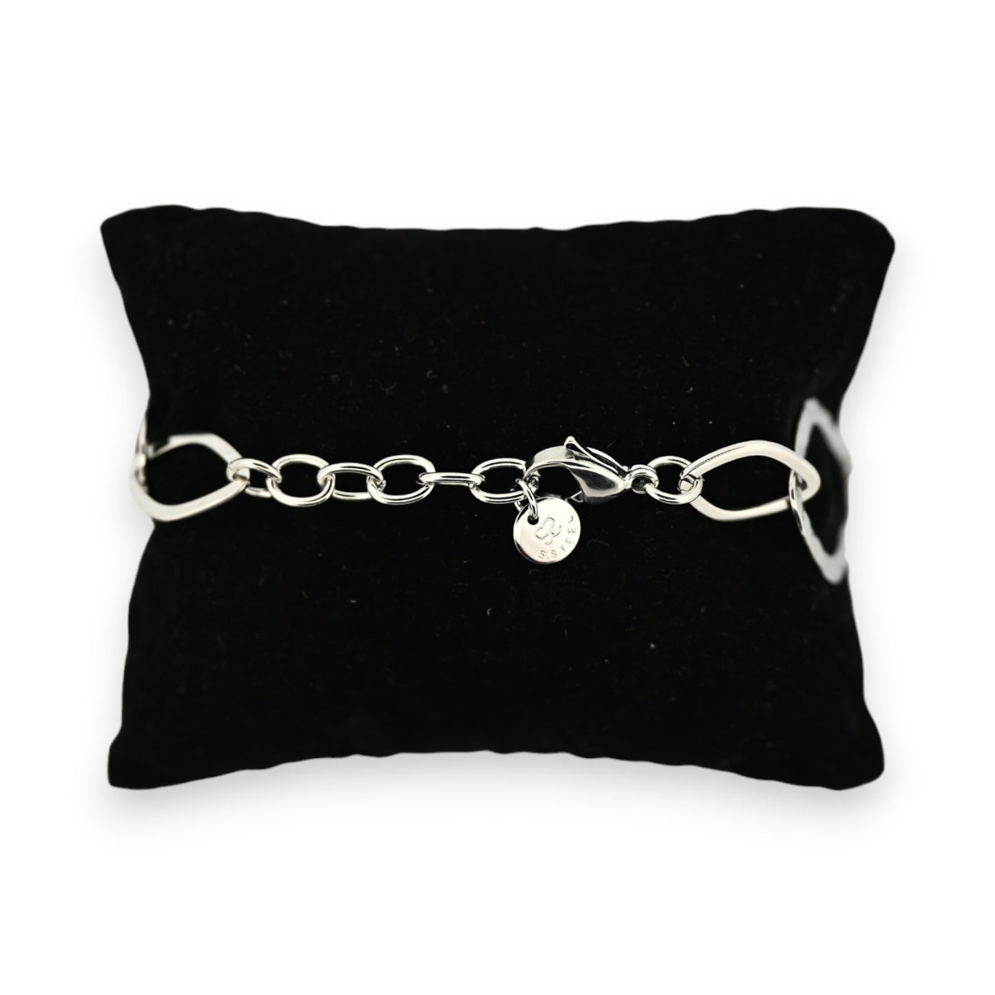 Silberfarbenes Stahlarmband auf schwarzem Kissen, mit großen Kettengliedern und einer runden Anhängerplakette