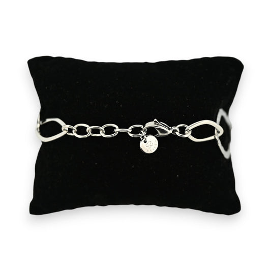 Silberfarbenes Stahlarmband auf schwarzem Kissen, mit großen Kettengliedern und einer runden Anhängerplakette