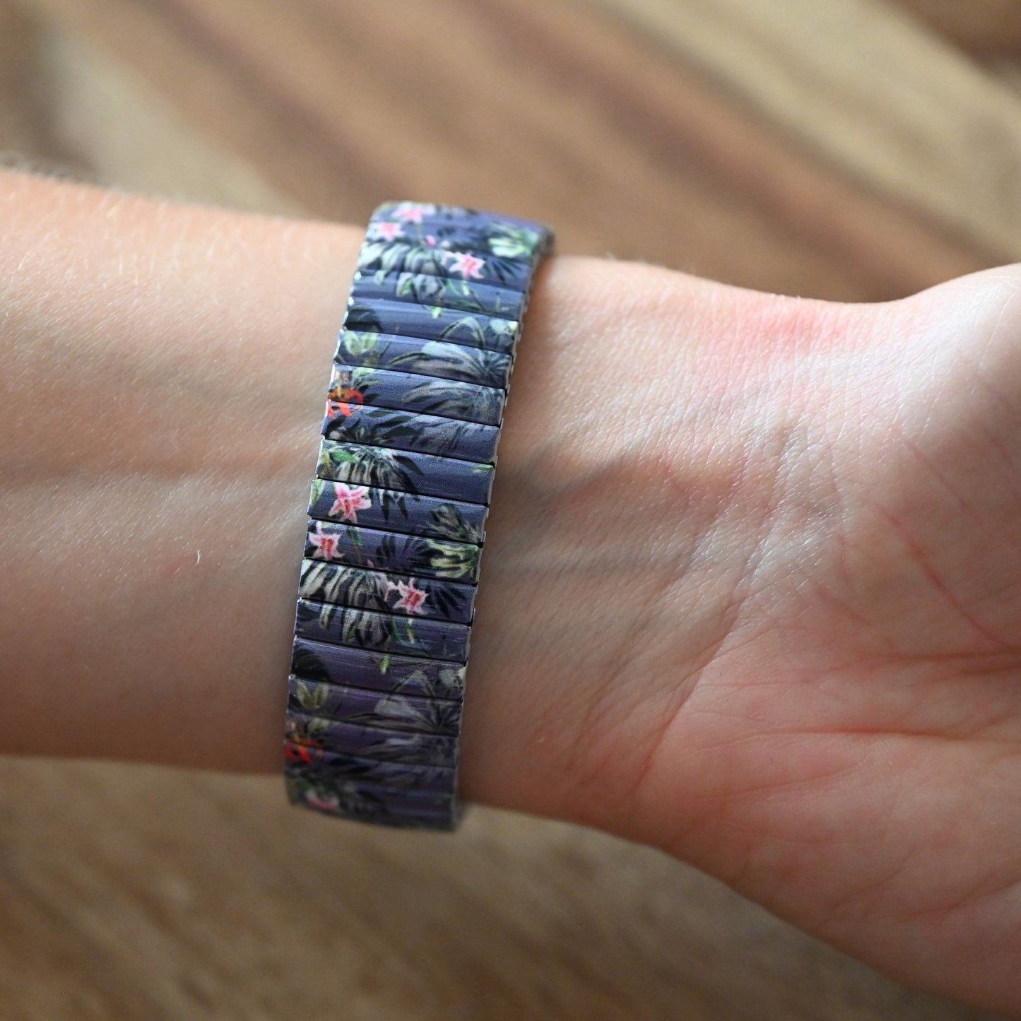 Elastisches Armband mit tropischem Blattmuster in Blau, Grün und Rosa auf einem Handgelenk