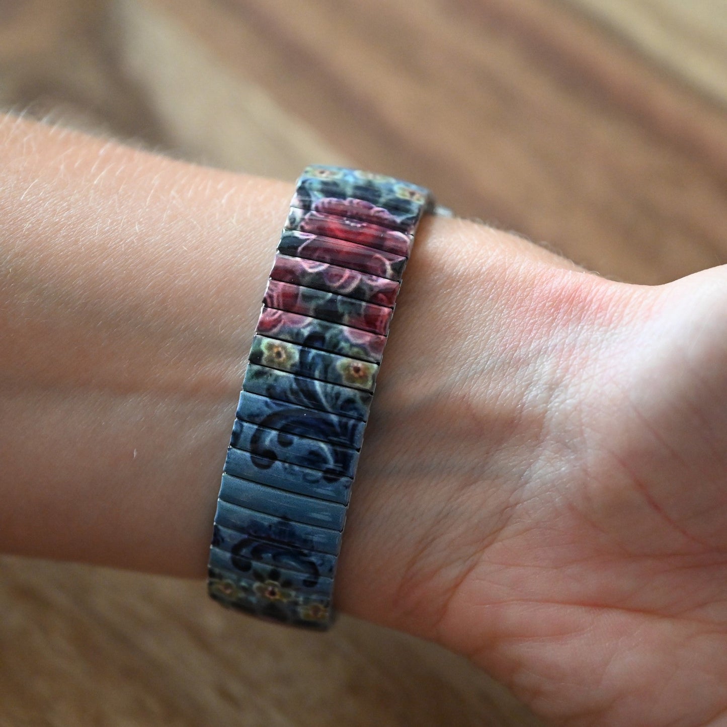 Vintage-Blumen-Armband mit blau-roten Blütenmustern auf elastischem Metall-Stretchband am Handgelenk