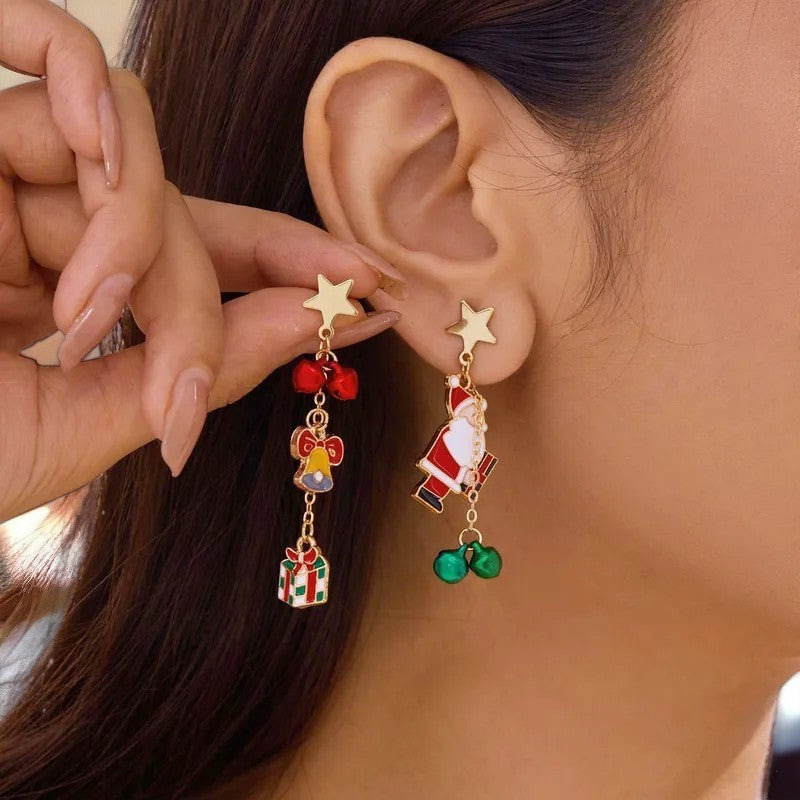 Weihnachtliche Ohrringe mit Stern, Santa, Glöckchen und Geschenk-Anhängern. Festlicher Modeschmuck am Ohr einer Frau.