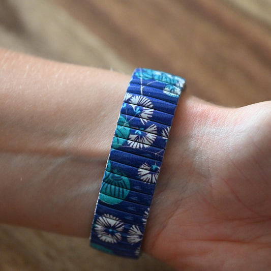 Elastisches Armband mit blau-türkisem Blumenmuster auf Handgelenk, detailreich und farbenfroh