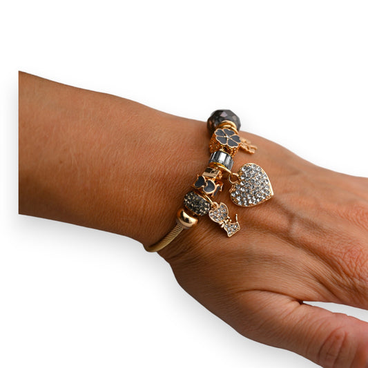 Goldenes Armband mit grauen und glitzernden Charms, darunter ein Herz und ein Hund mit Strasssteinen verziert