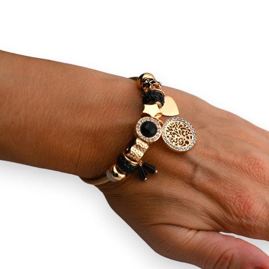 Goldenes Charm-Armband mit schwarzen Elementen, Schädel und Baum des Lebens Anhänger auf brauner Haut