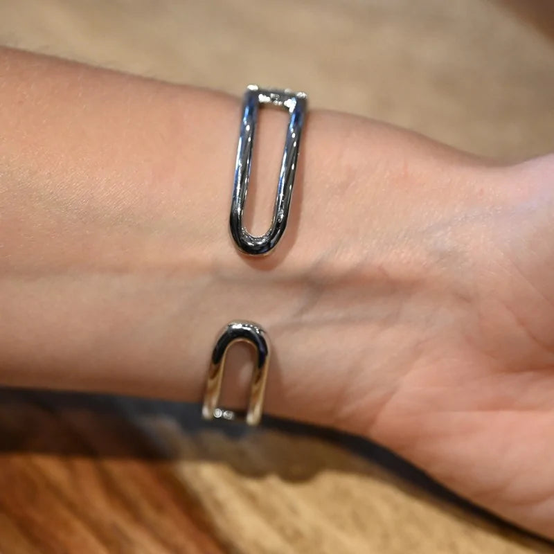 Offenes silbernes Armband mit zwei U-förmigen Enden an einem Handgelenk
