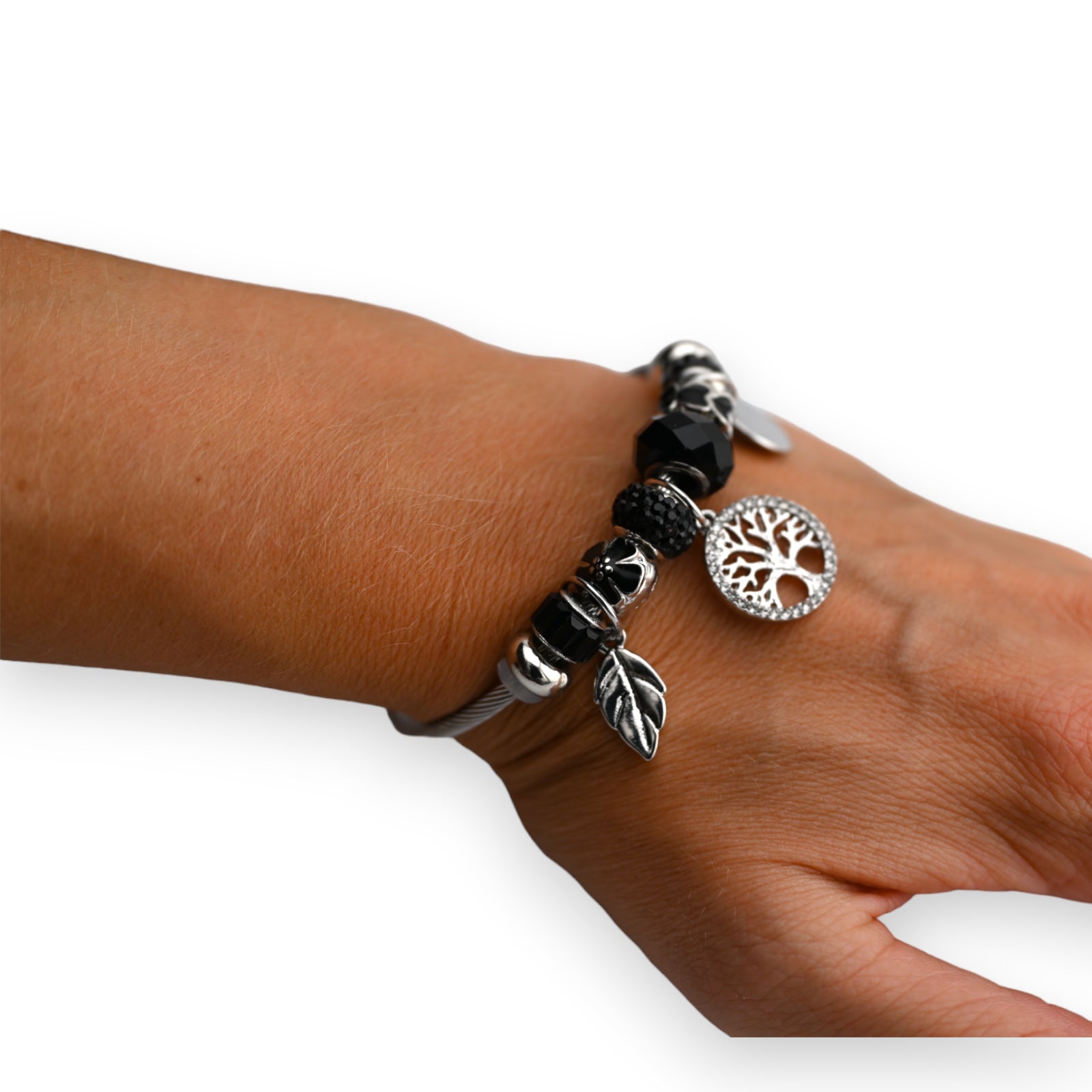 Elegantes Charm-Armband mit schwarzen Perlen, silbernen Anhängern und Baum des Lebens Symbol auf weiblichem Handgelenk