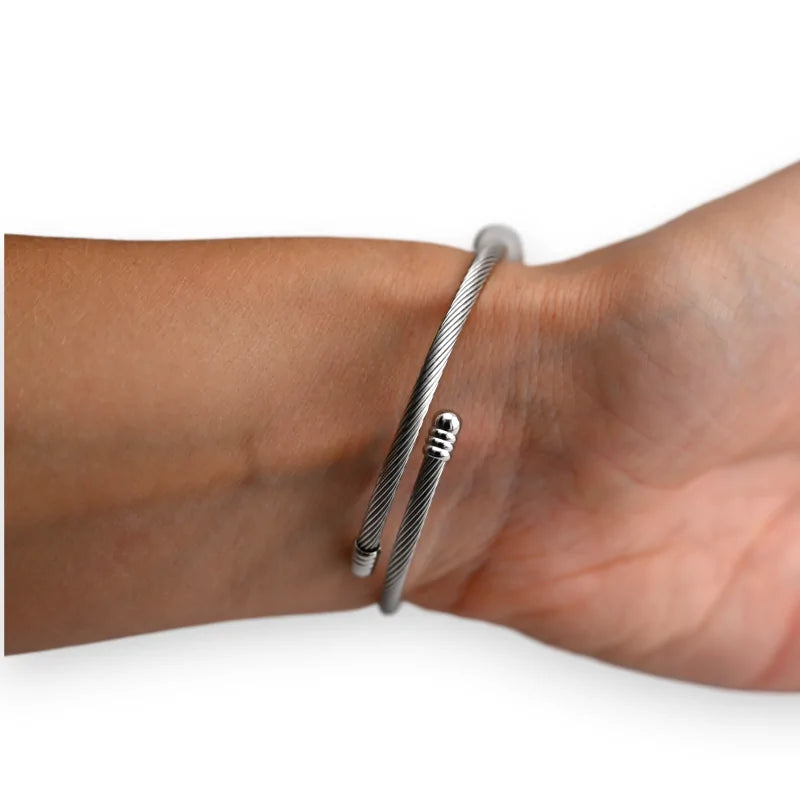 Starres silberfarbenes Armband aus Metallkabel mit verstellbarem Verschluss, getragen am Hand...
