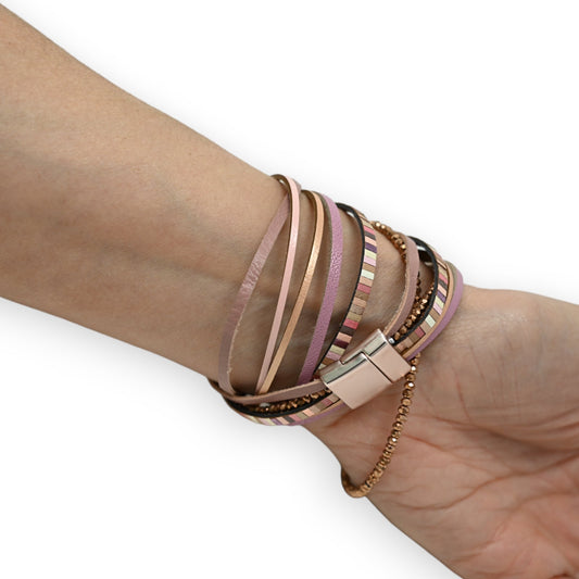 Mehrschichtiges Armband in Rosatönen mit Lederstreifen, Metallketten und Magnetverschluss um ein Handgelenk gewickelt