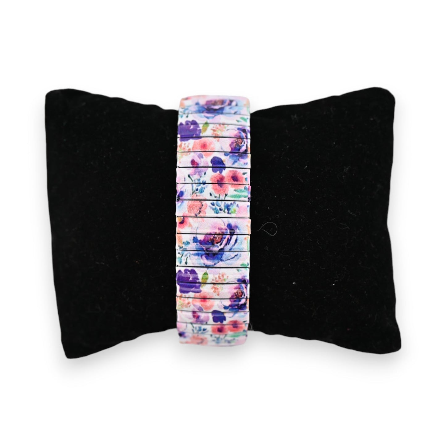 Elastische Armbanduhr mit buntem Blumenmuster auf schwarzem Samtkissen, perfekt für den Frühling und Sommer