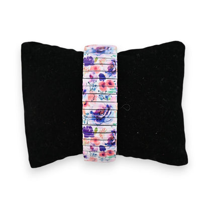 Elastische Armbanduhr mit buntem Blumenmuster auf schwarzem Samtkissen, perfekt für den Frühling und Sommer