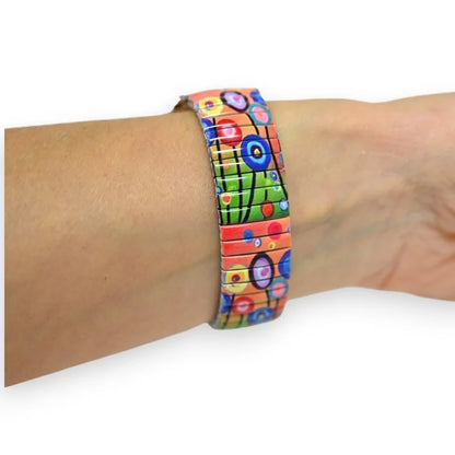 Buntes elastisches Armband mit abstrakten Motiven am Handgelenk getragen, künstlerischer Stil