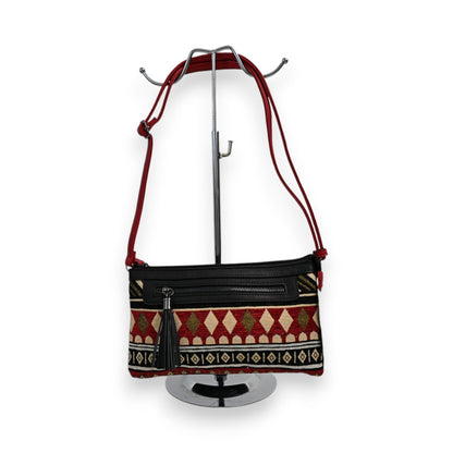 Ethnische Umhängetasche mit Tribal-Muster in Rot und Schwarz, Reißverschluss und Quaste, hängend an Metallständer