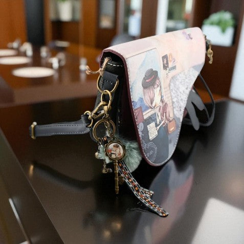 Vintage-Schultertasche mit Mädchenmotiv und dekorativen Anhängern in Nahaufnahme