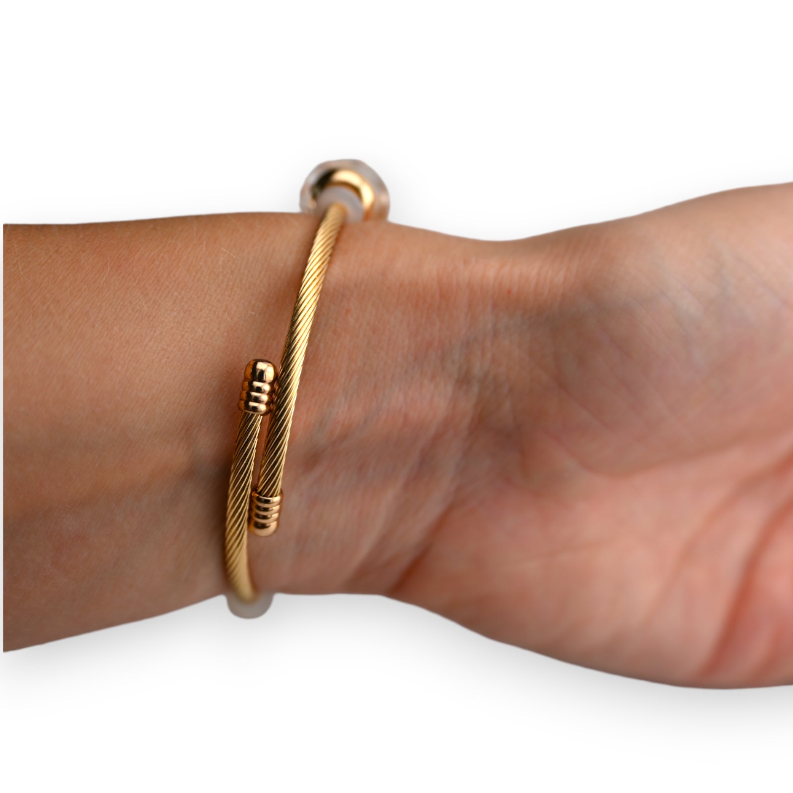 Goldenes Armband mit starrem Design und weißen Akzenten am Handgelenk getragen, eleganter Schmuck für Damen