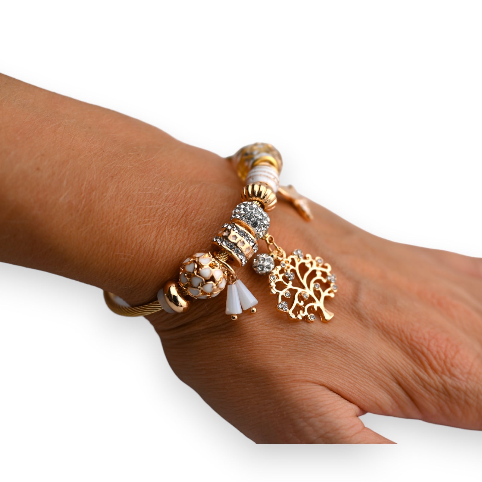 Goldenes Armband mit weißen Perlen und Charms, darunter ein glitzernder Lebensbaum-Anhänger auf Handgelenk