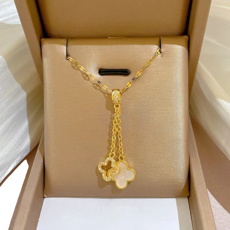 Goldene Halskette mit Doppelanhänger in Kleeblattform, ein Anhänger mit Perlmutt, in eleganter Schmuckbox präsentiert