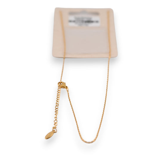 Filigrane goldene Halskette auf beigem Karton, mit dünner Kette und Verlängerungsglied, minimalistisches Design