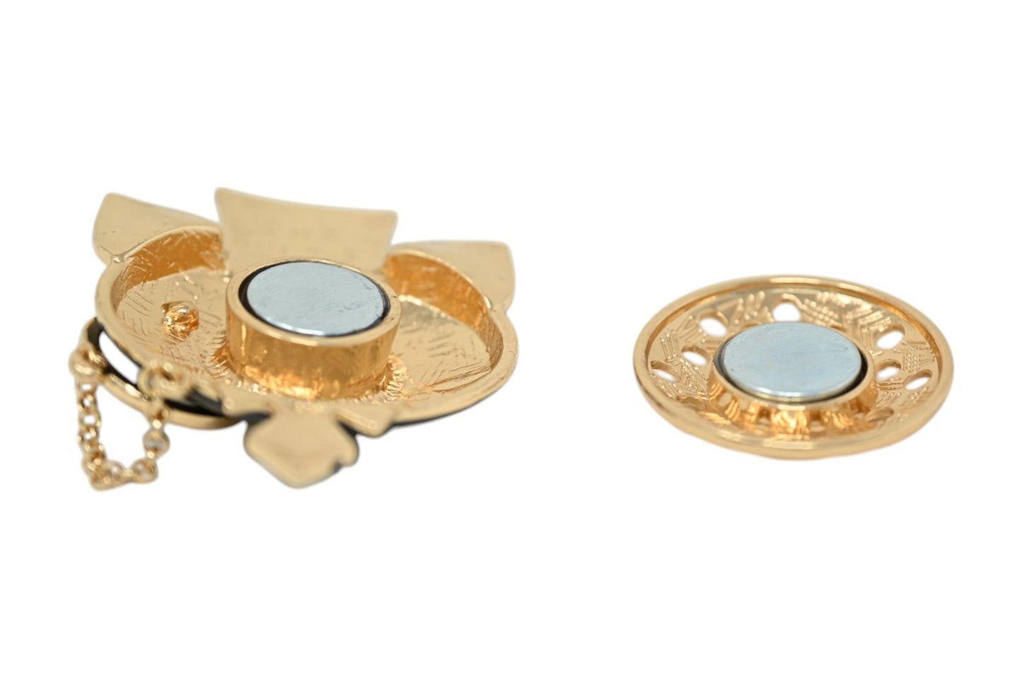 Goldene magnetische Brosche mit Blütenform und rundem Magneten, daneben kleinere runde Brosche mit Ornamenten