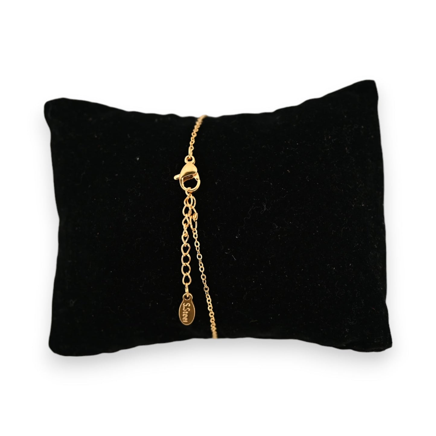 Goldenes Stahlarmband auf schwarzem Samtkissen, mit rundem Anhänger und Sterngravur, elegantes Schmuckstück